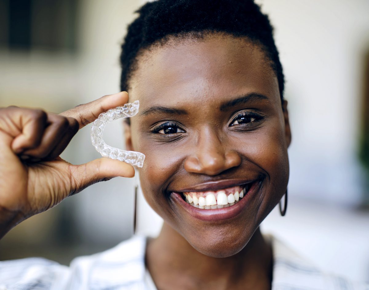 woman-holding-aligners-smiling
